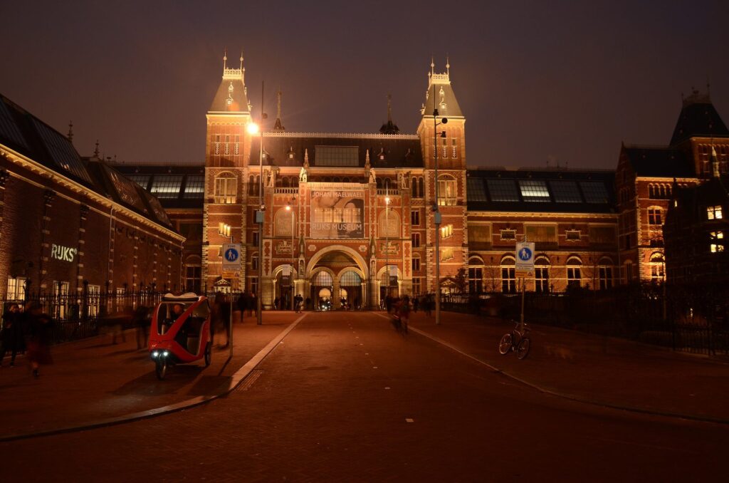Beleuchtete Fassade und Durchgang des Rijksmuseums in Amsterdam am Abend