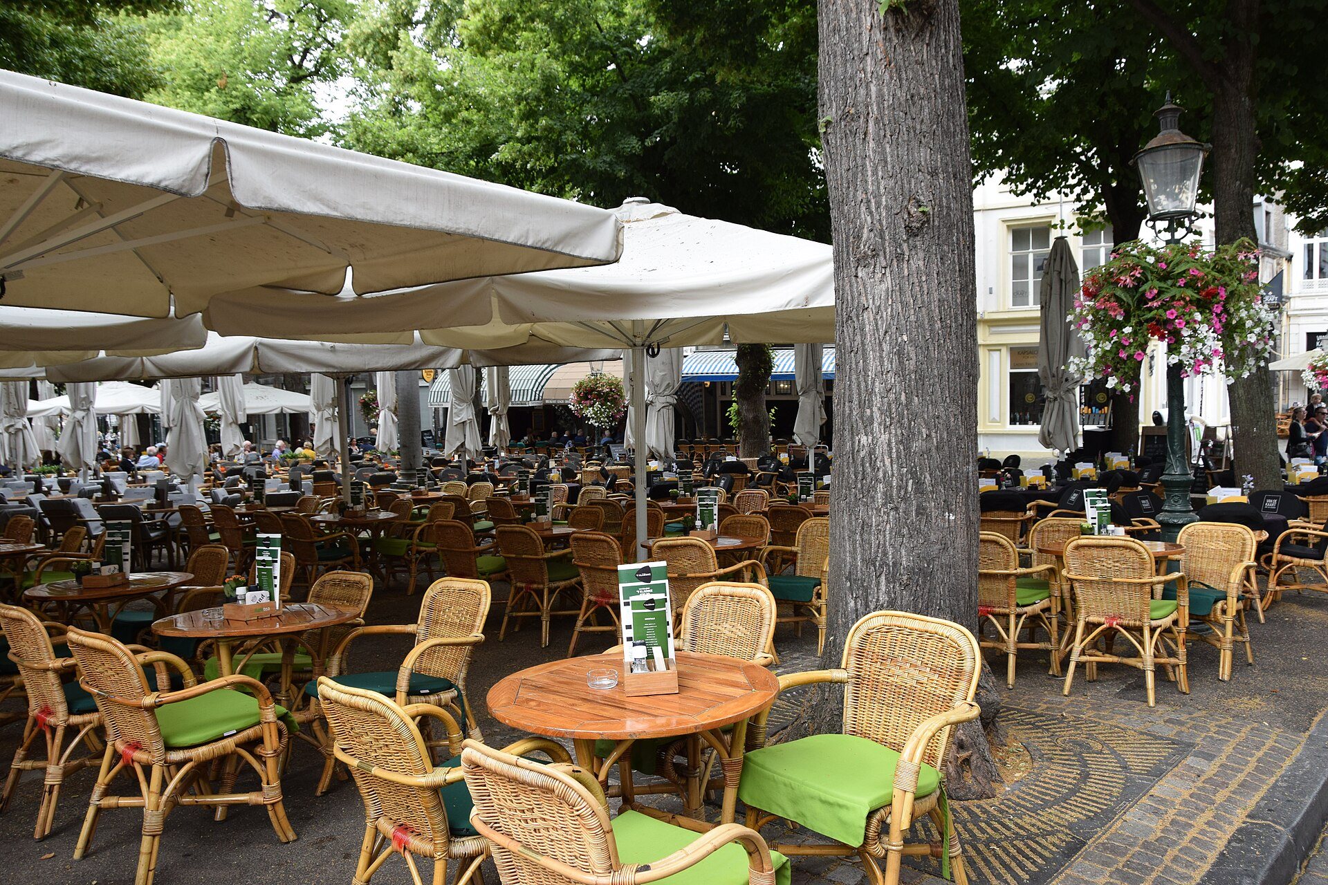 Restaurantterrasse mit Korbstühlen und Sonnenschirmen in der Altstadt von Maastricht