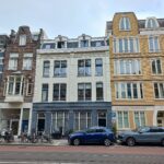 Umweltzonen in niederländischen Städten: Was 2025/2026 beachten? Innerstädtische Straße mit Autos, Fahrrädern und Altbauten in Amsterdam