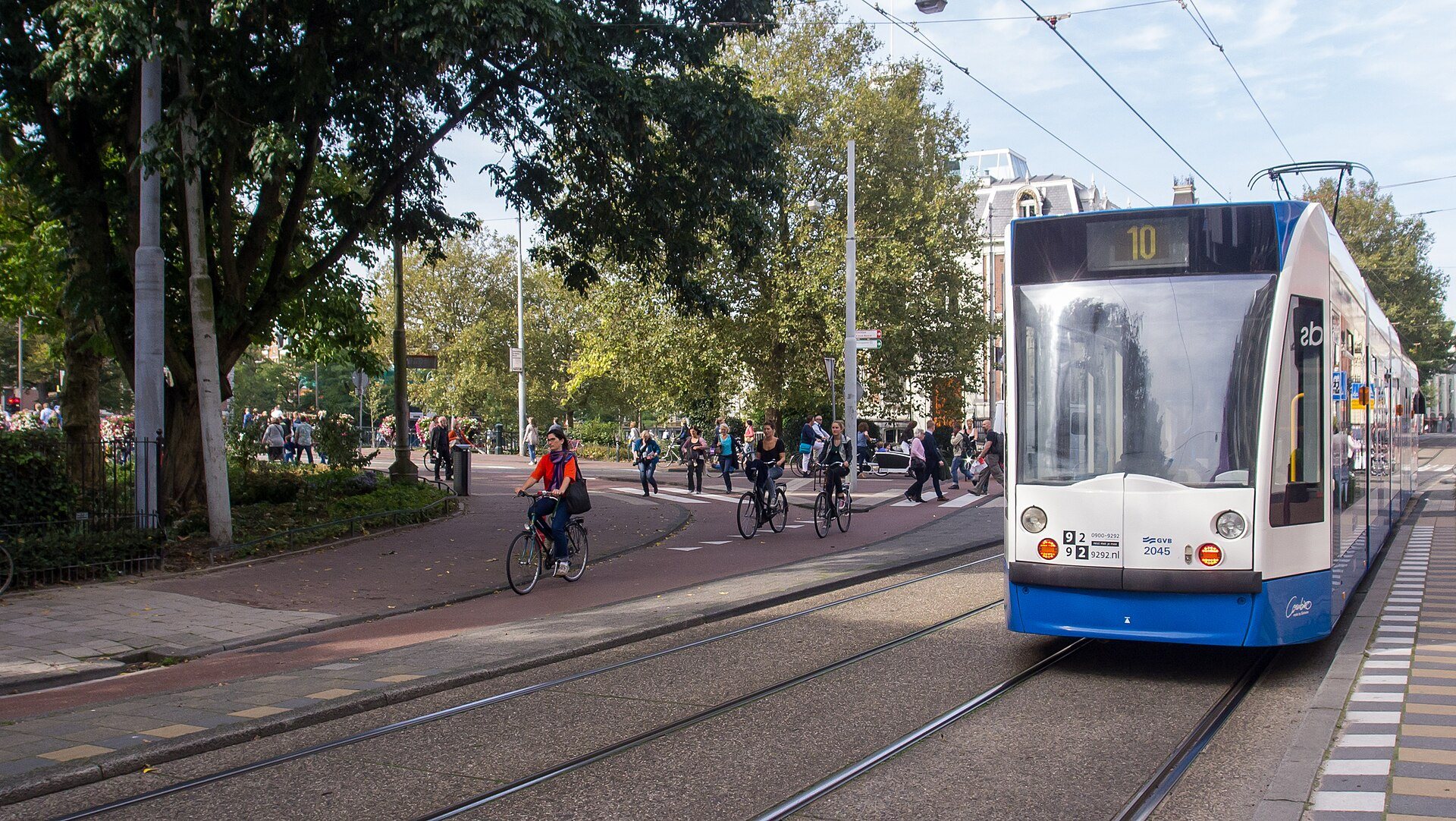 Radfahrer auf einem roten Radweg neben einer Straßenbahn in Amsterdam