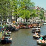 Amsterdam abseits der Hauptattraktionen: Viertel, Museen und Parks Gracht im Amsterdamer Jordaan mit Hausbooten und kleinen Booten im Sommer