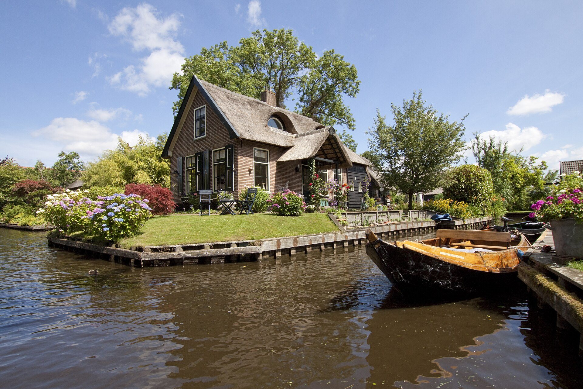 Reetgedecktes Haus mit Garteninsel und Punter an einer Gracht in Giethoorn