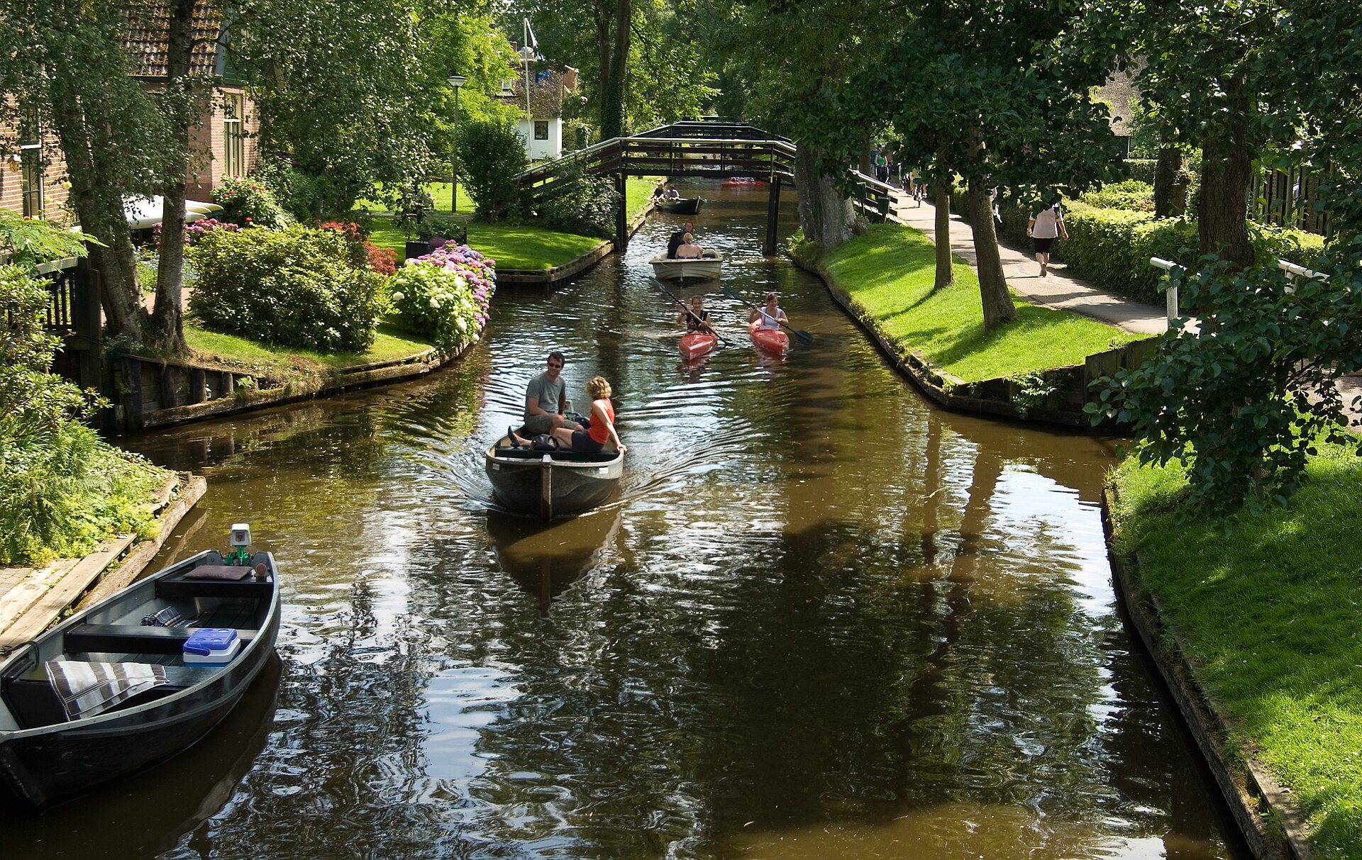 Kleine Boote auf einer Gracht mit Holzbrücke im Dorf Giethoorn