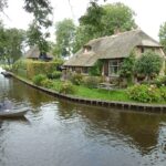 Giethoorn: Das niederländische Venedig entdecken Reetgedecktes Bauernhaus an einer Gracht in Giethoorn mit Ausflugsboot