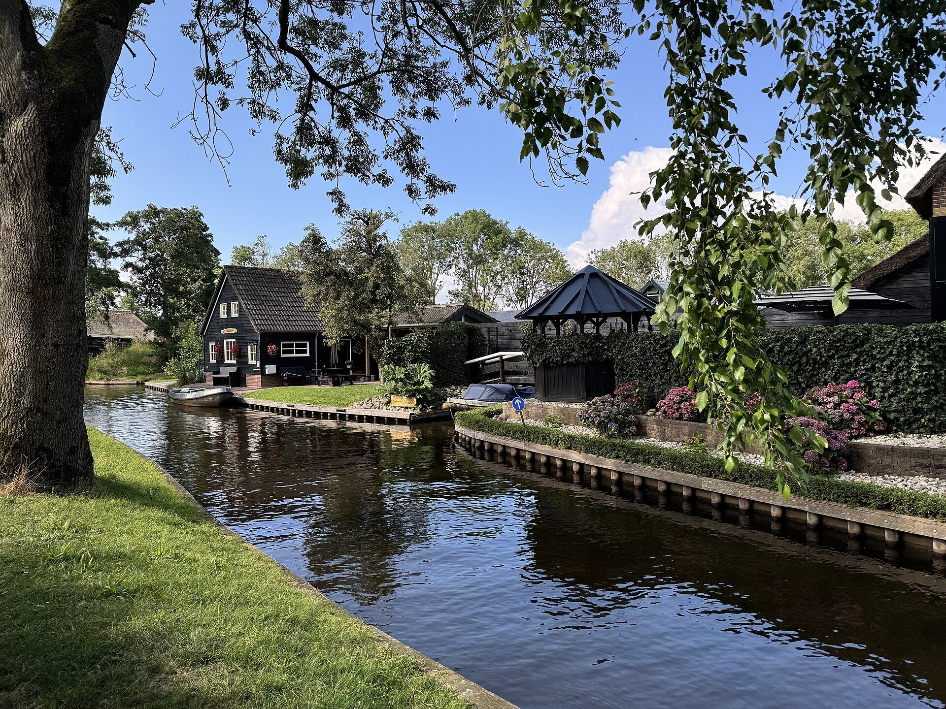 Gracht mit Gärten und Holzhäusern im Dorfkern von Giethoorn im Sommer