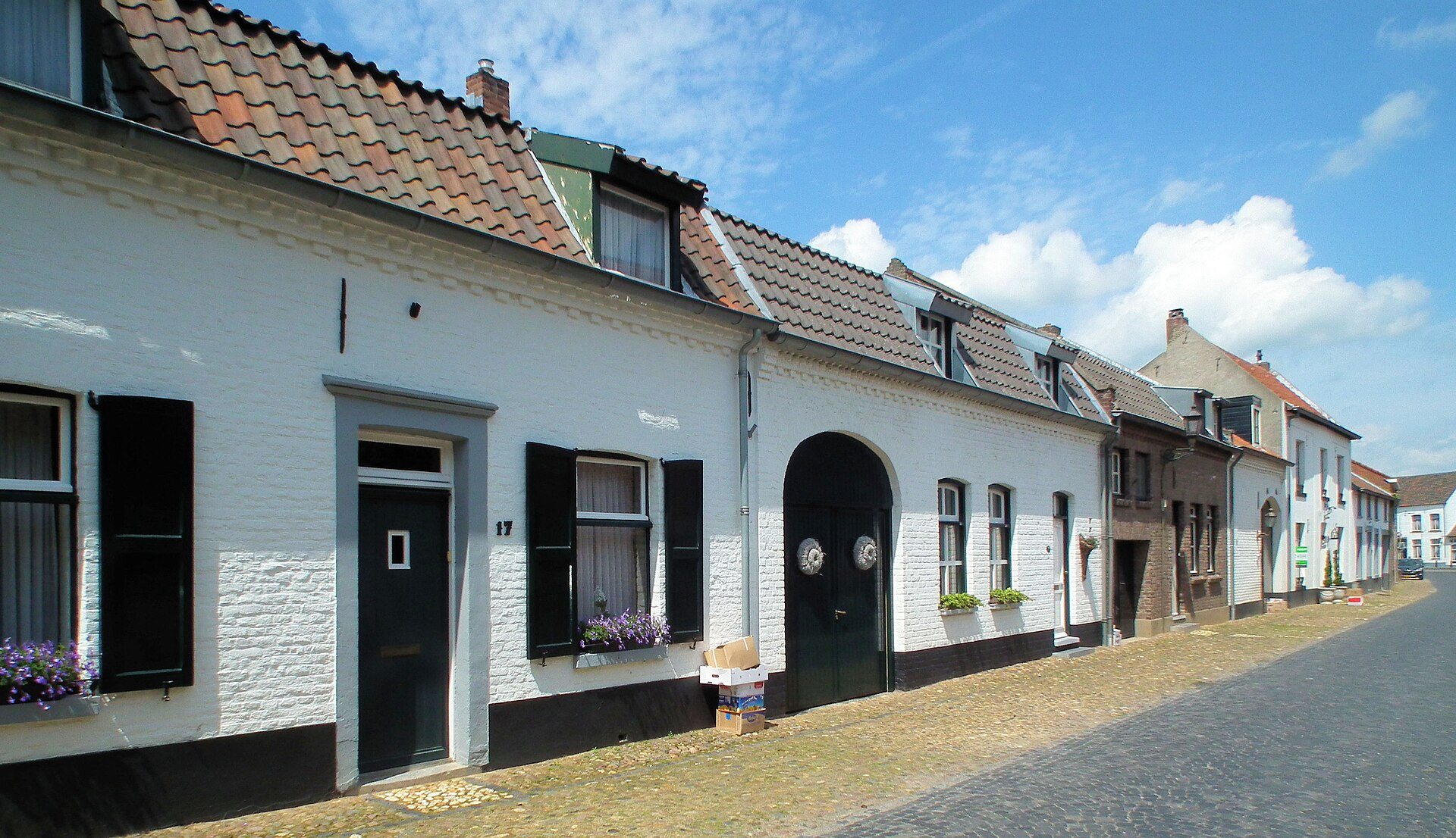 Reihe weiß gestrichener Wohnhäuser an einer Kopfsteinpflasterstraße in Thorn