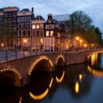 Studieren in den Niederlanden: Amsterdam Beleuchtete Brücken an der Ecke Reguliersgracht und Keizersgracht in Amsterdam
