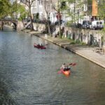 Kajakfahren auf den Grachten: Eine andere Perspektive der Niederlande Kajakfahrer auf der Oudegracht in Utrecht zwischen Werftkellern und Brücke
