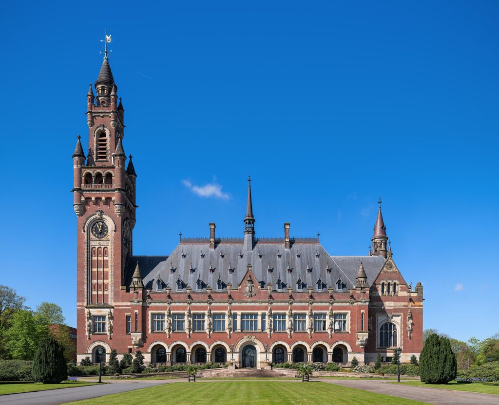 Der Friedenspalast in Den Haag mit Uhrturm und Rasenfläche unter blauem Himmel