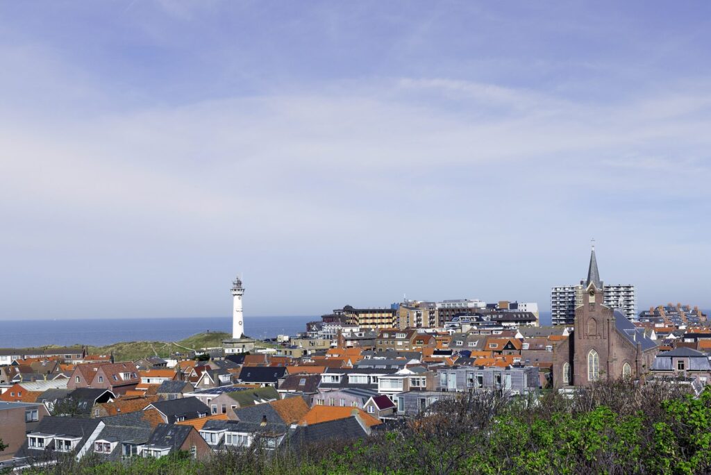 Blick über die Dächer von Egmond aan Zee mit Leuchtturm und Kirche am Meer