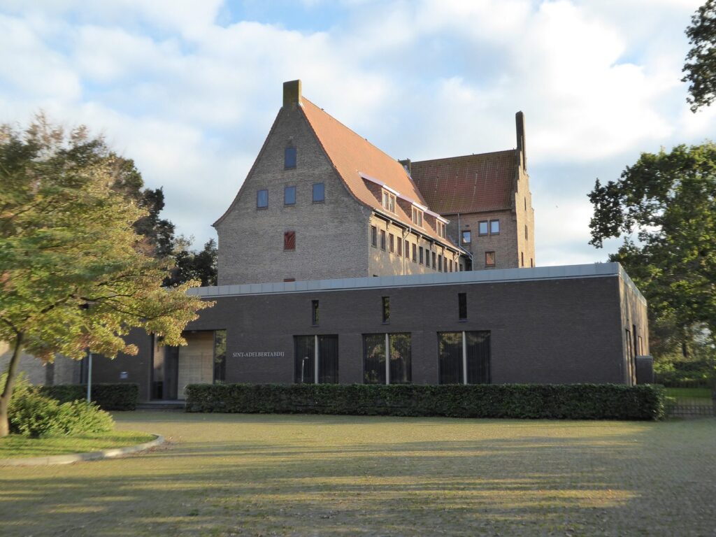 Backsteinbau der Sint-Adelbertabdij in Egmond-Binnen hinter einer Rasenfläche