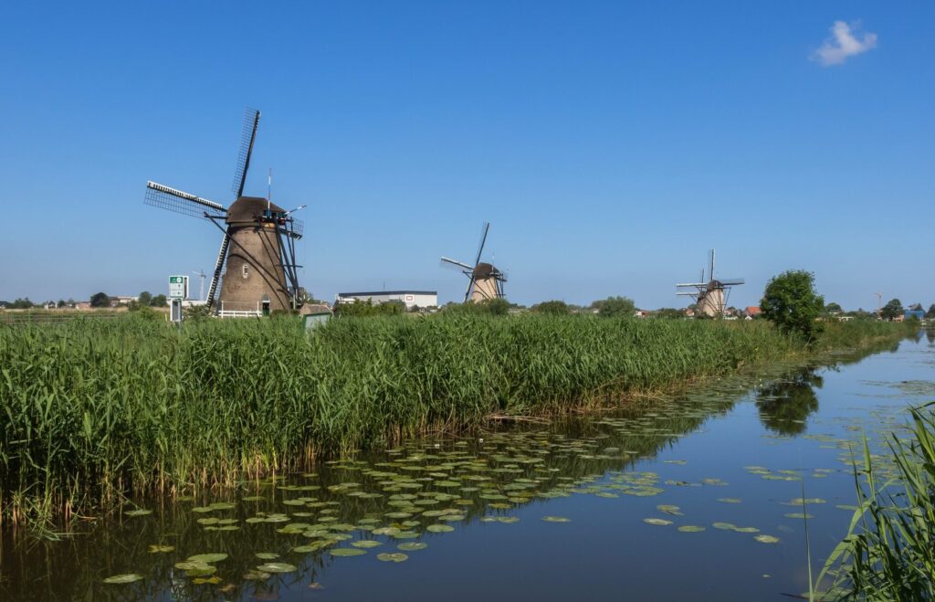 Reihe der Nederwaard-Mühlen von Kinderdijk am Wasser unter blauem Himmel