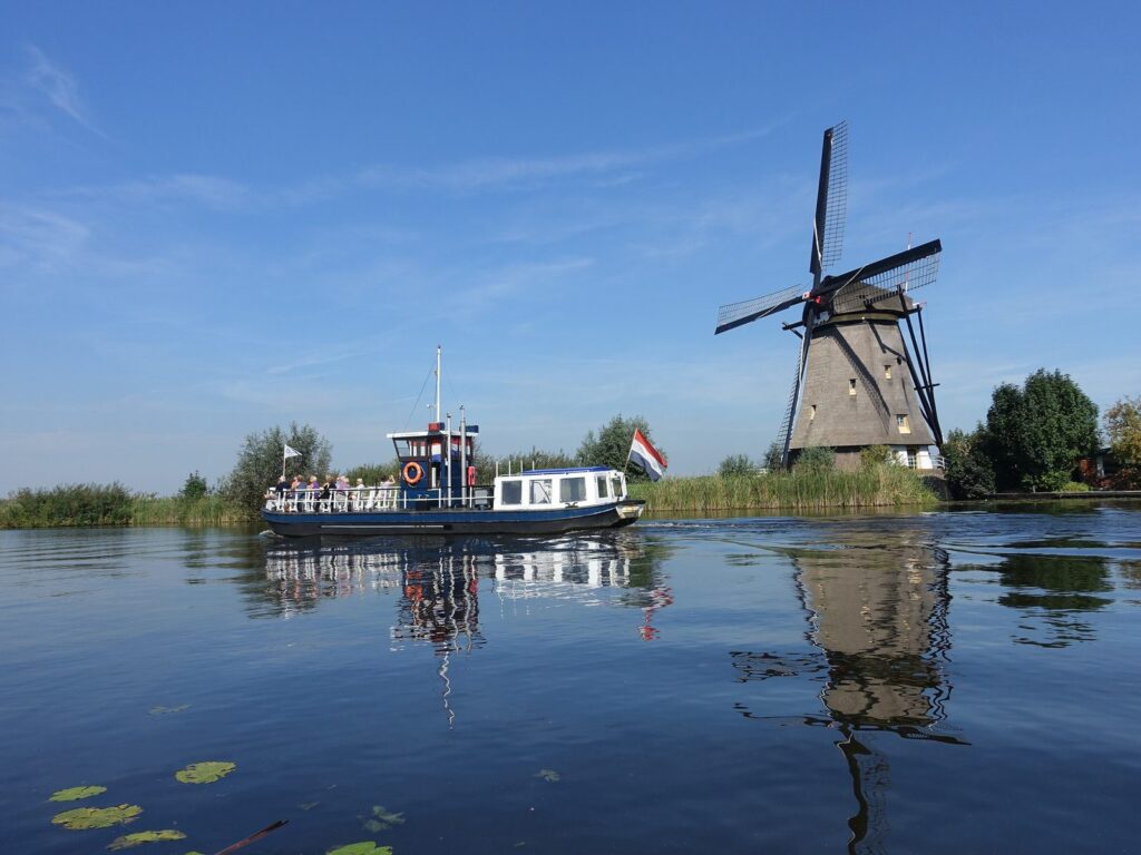 Rundfahrtboot vor einer Overwaard-Mühle auf dem Wasser in Kinderdijk