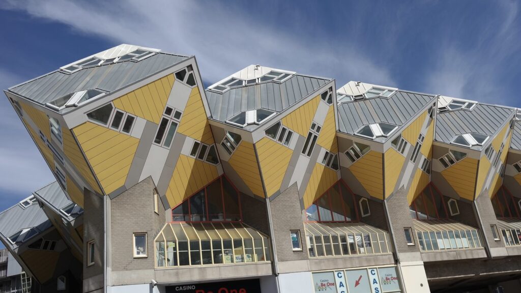 Gelbe gekippte Kubushäuser von Piet Blom in Rotterdam vor blauem Himmel