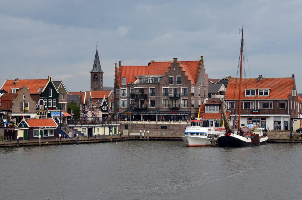 Hafen von Volendam mit Segelschiffen, Häuserzeile am Deich und Kirchturm