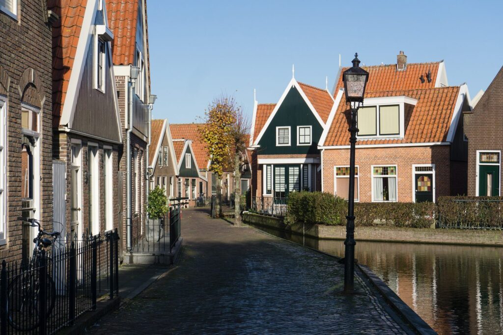 Schmale Gasse mit Holzhäusern, Laterne und Gracht im alten Ortskern von Volendam